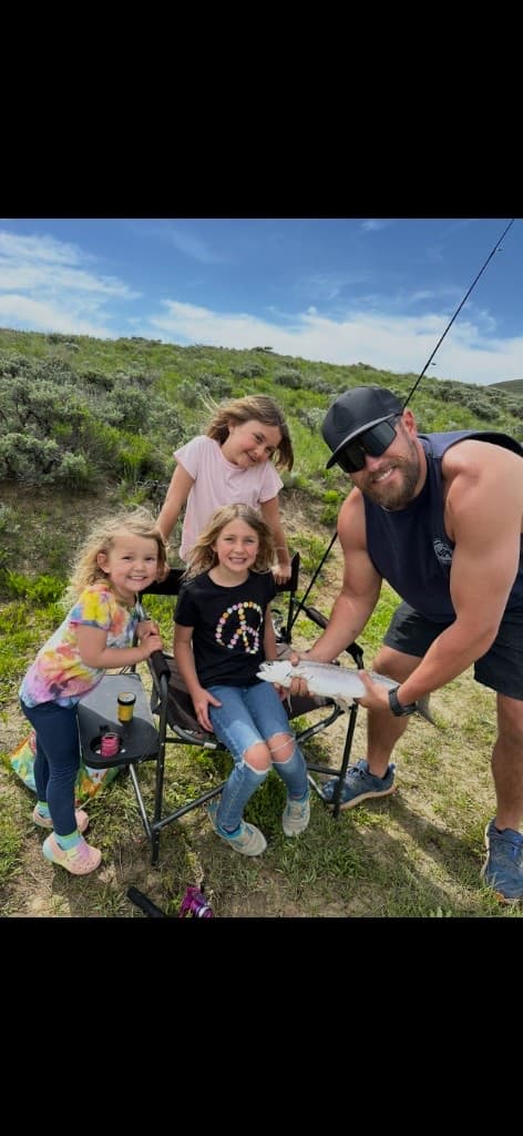 Nick kneeling with a trout after a family fishing trip